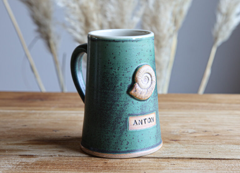 grün-blau gesprengkelter Tonkrug mit Schnecke und Namen "Anton"